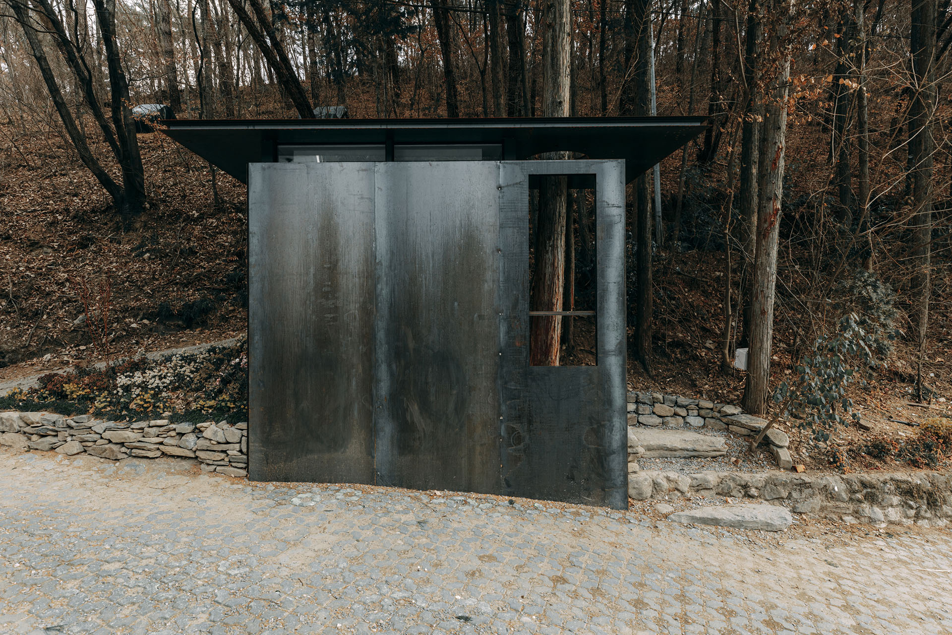 숲길 모퉁이의 RES-TREE. 내후성 강판 외벽과 세로로 뚫은 정면 강판
